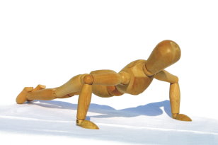 eine Holzfigur beim Liegestütz